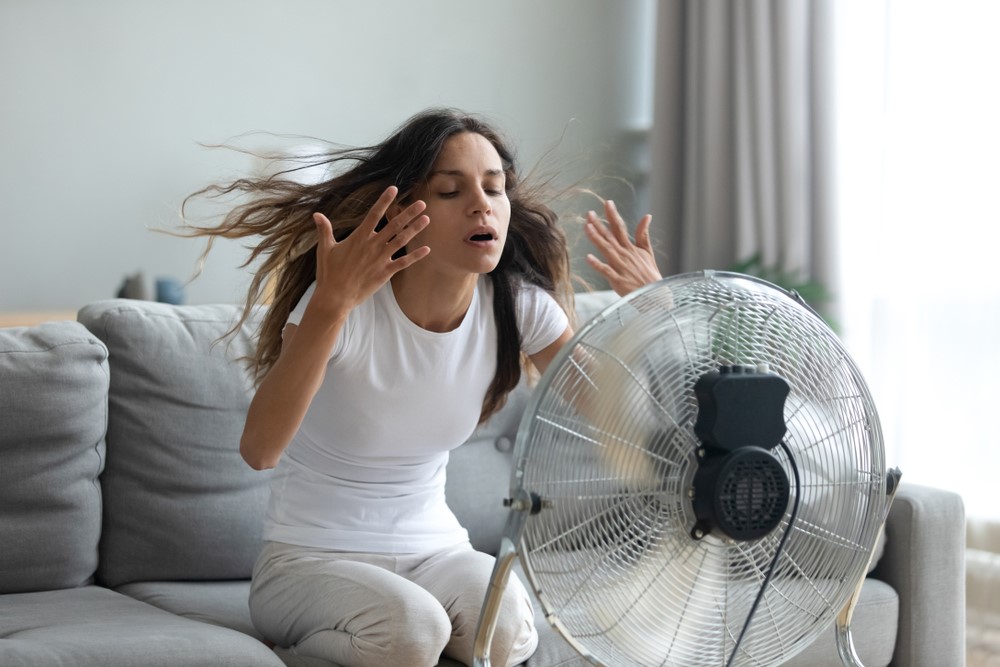girl feeling hot sitting in front of fan
