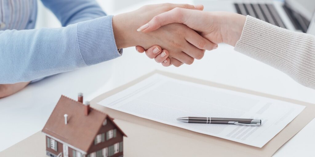 estate broker and customer shaking hands after signing a contract